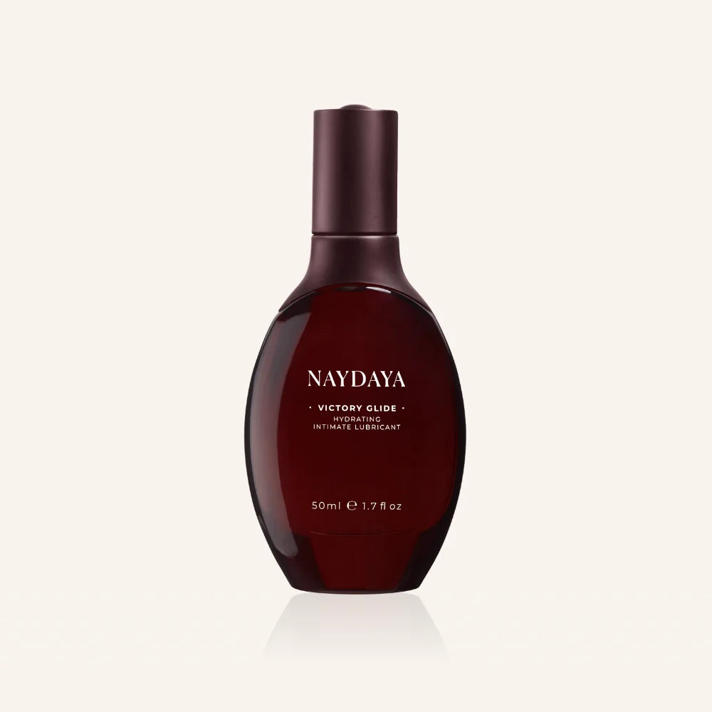 A 50ml bottle of NAYDAYA Victory Glide vibrating intimate lubricant, shown on a clean off-white background with a soft reflection.